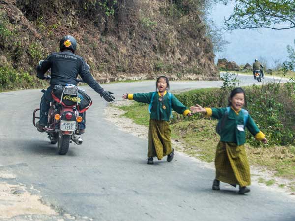 royal enfield tour of bhutan riders passing kids