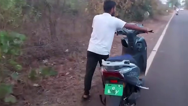 ev owner pushes electric scooter 20km