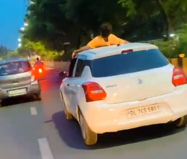 Man performs dangerous stunts on moving car 